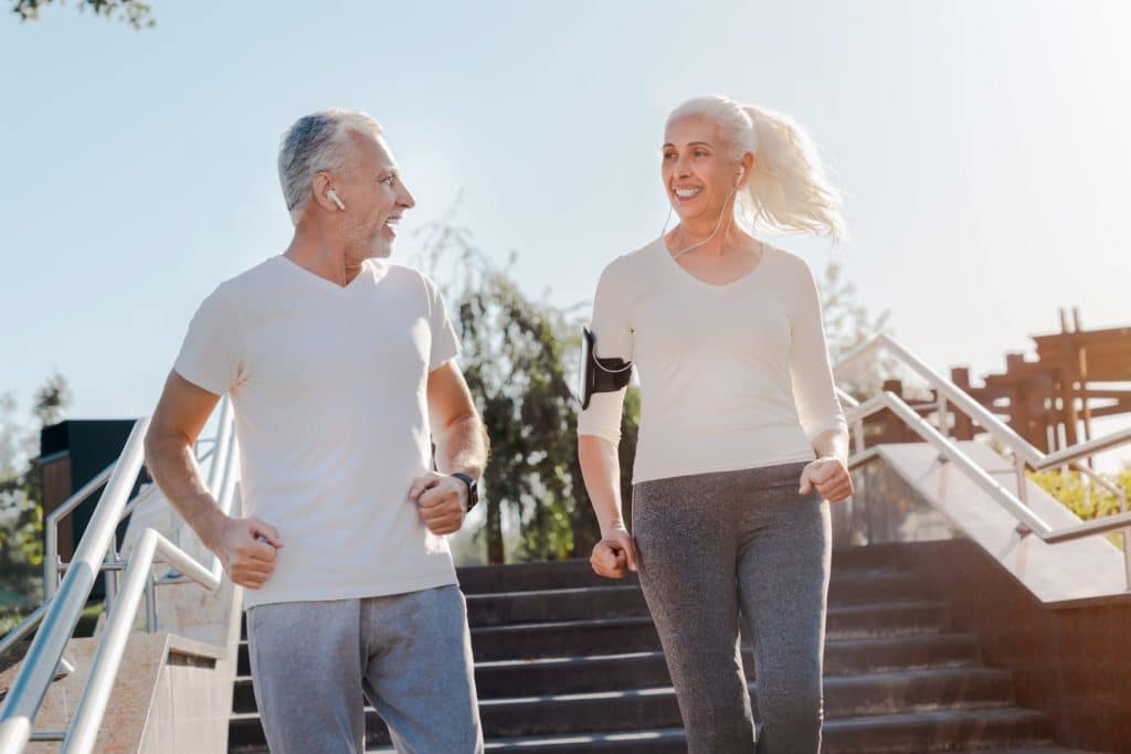 Close up shot of sporty happy elderly couple running down the stairs with look on each other
