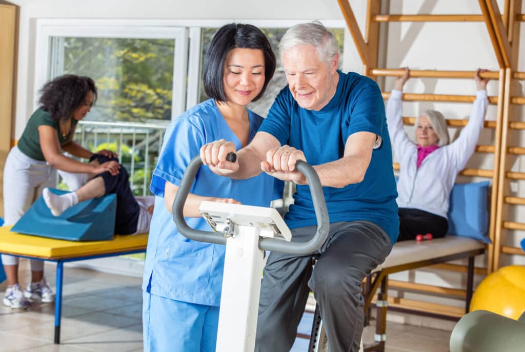 A senior man receives guidance for cardio exercise from a physical therapist