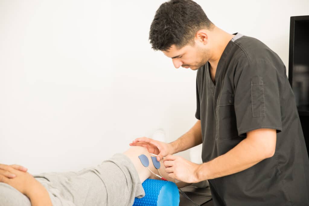Image of a physical therapist applying E-stim to a senior patient for knee problems