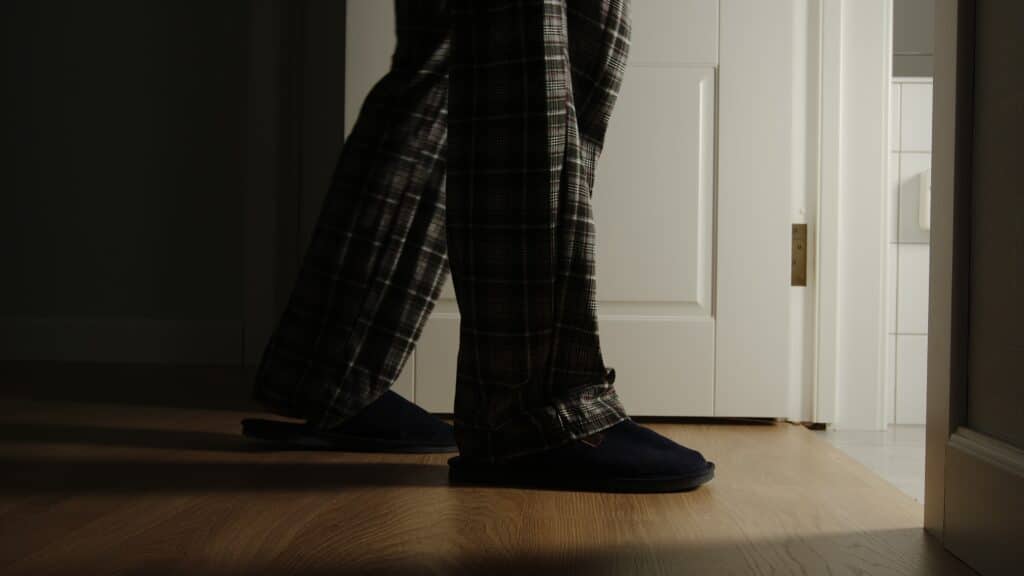 Image of a senior man walking to the restroom in slippers at night due to urge incontinence