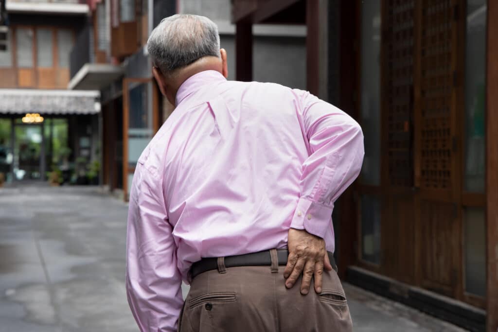 Senior man rubs his hip from sciatica pain