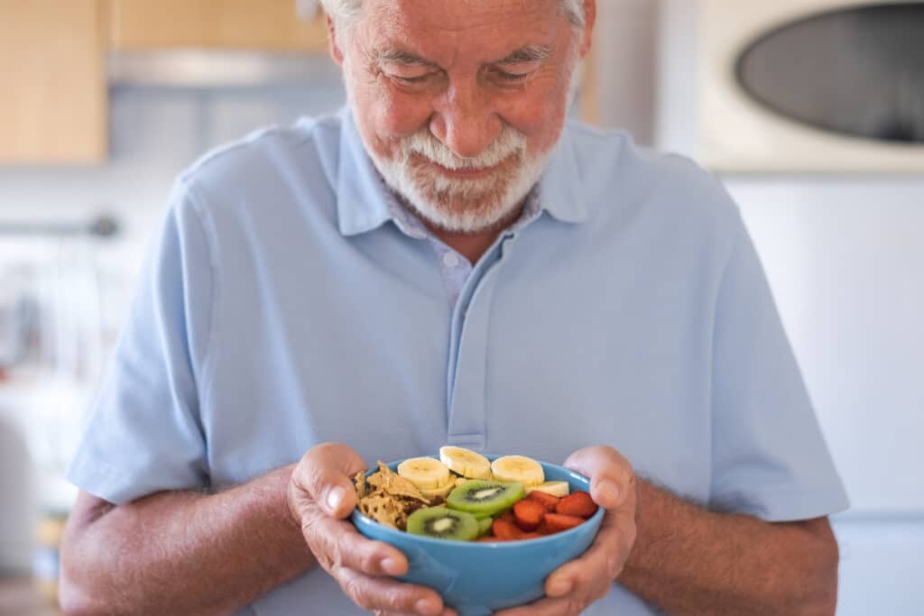 Senior man preparing to enjoy a bowl of oatmeal with fresh fruit