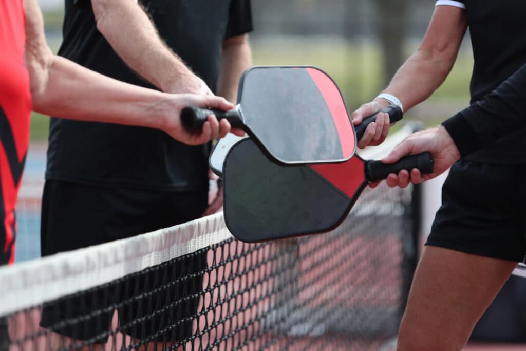 Pickleball injuries: four senior man touch paddles before a match