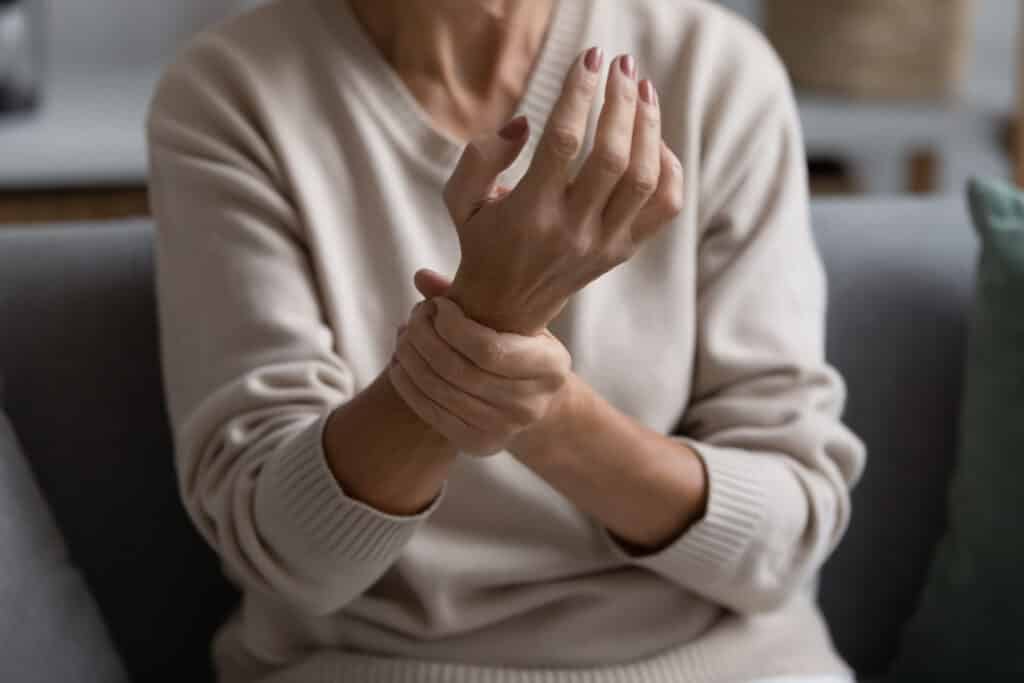 Older woman rubs her wrists due to neuropathy pain