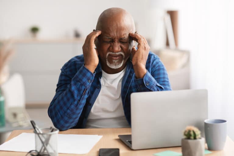Senior African American man with a headache at his desk