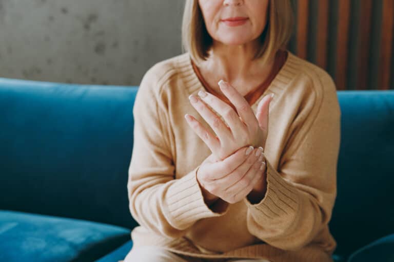 An older woman with Dupuytren's Contracture rubbing her pianful palm
