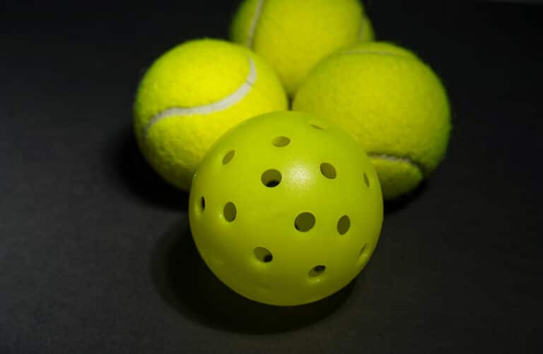Pickleball vs tennis: a cluster of tennis balls and pickleballs arranged together