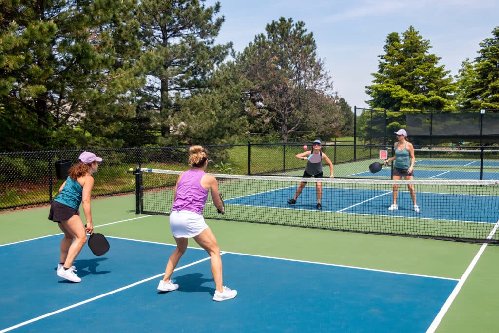 Senior women play competitively on an outdoor court.
