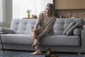 Image of older blonde woman rubbing her heel from plantar fasciitis pain