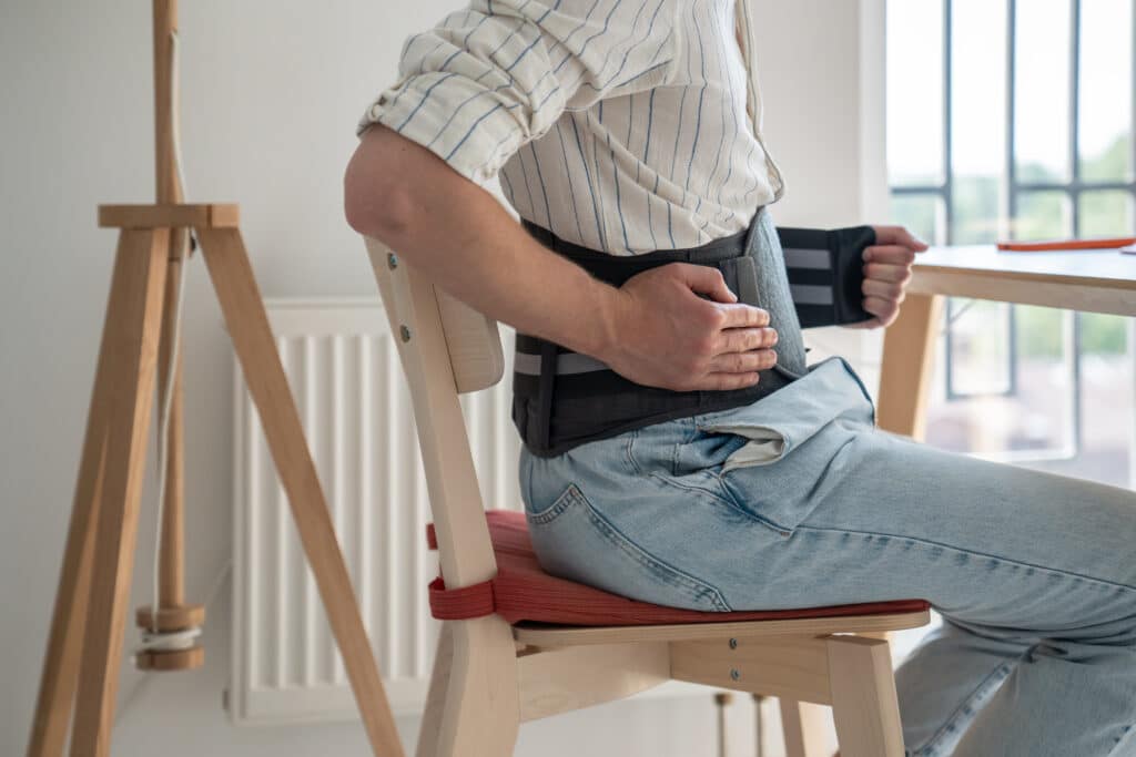 Man seated at a desk wearing a spinal decompression belt.