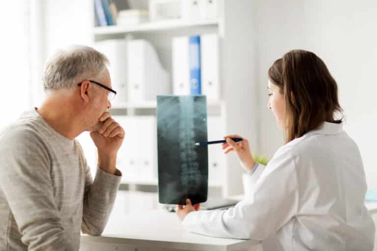 Spinal Decompression at Home: image of an older man looking at a spinal xray with his female doctor