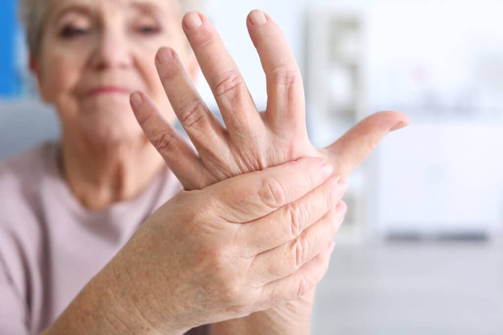 Image of an older woman rubbing her painful wrist from arthritis of the hand and wrist