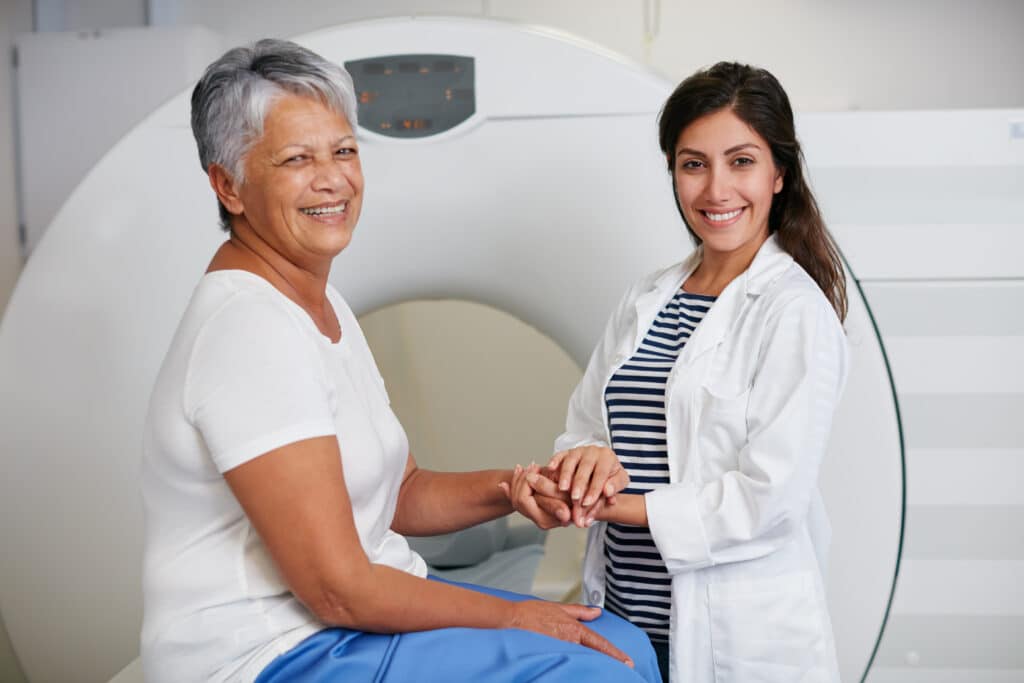 Image of a happy senior woman with her doctor preparing for a magnetic resonance imaging scan (MRI) for spinal osteoporosis