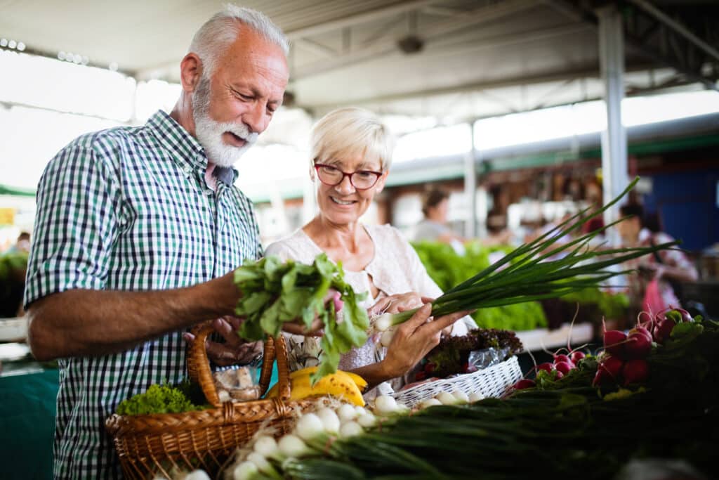 A senior couple buying produce at the farmer's market to encourage a healthy lifestyle.