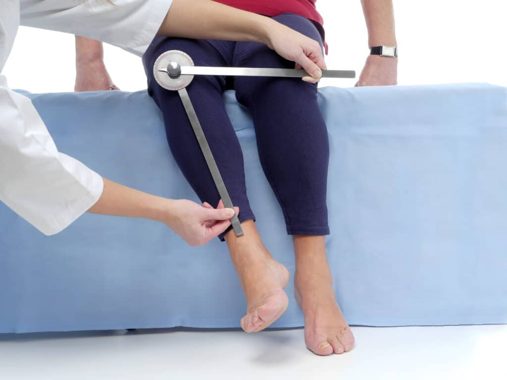 Image of a physical therapist measuring an older female client's external hip rotation with a goniometer