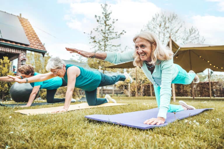 Core strength for seniors: image of a group of senior women doing bird dog floor exercise for core strength outdoors