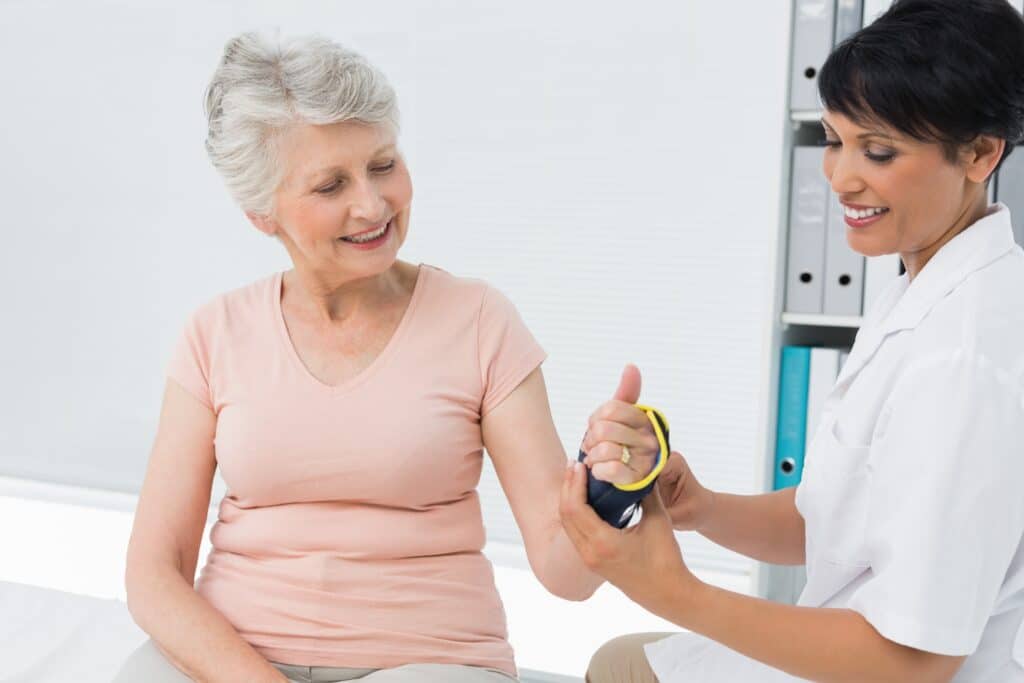 Senior Woman Being Fitted for Wrist Brace By Doctor.