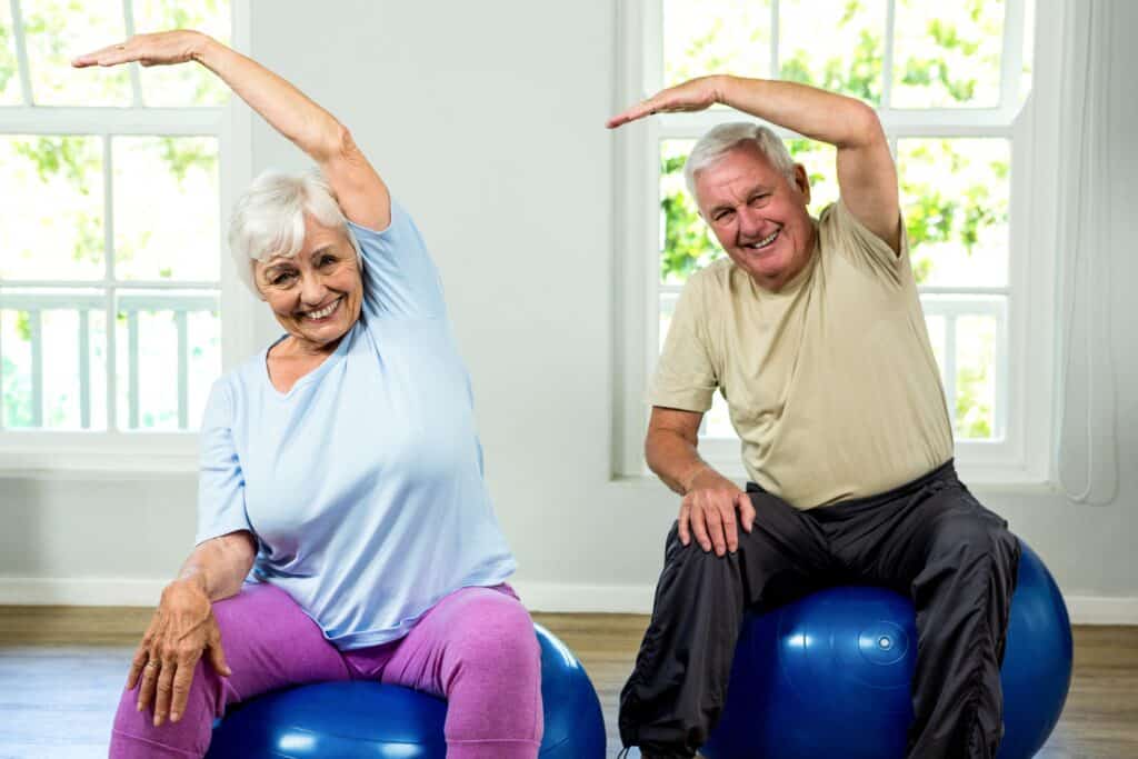 Image of a senior couple doing a side bending core movement while seated on a swiss ball.