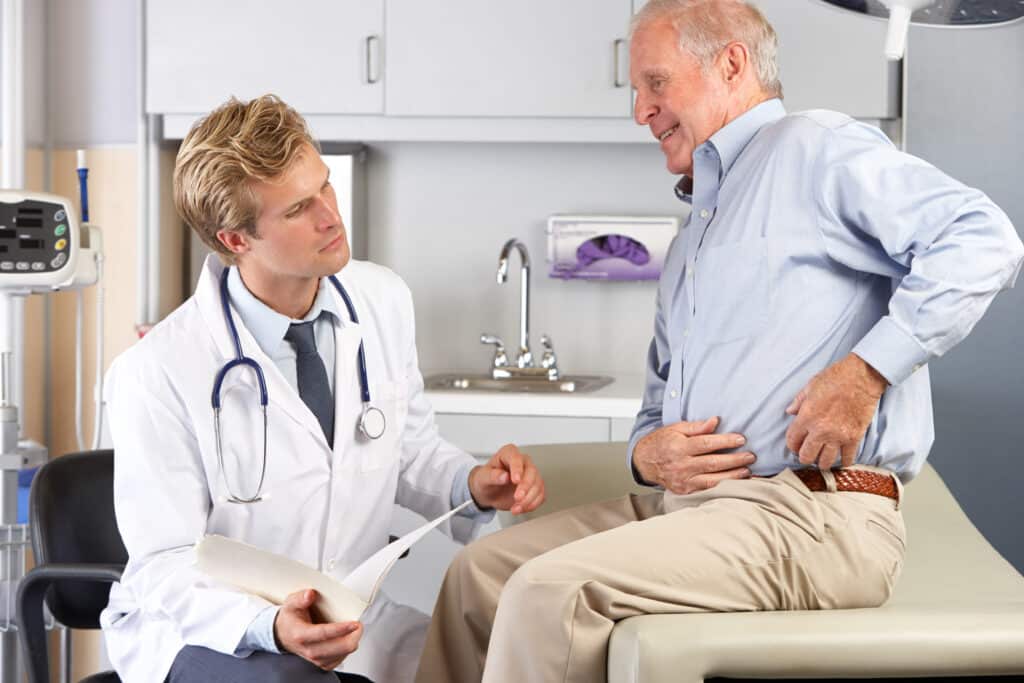 Image of a senior man talking to his doctor about hip pain while sleeping.