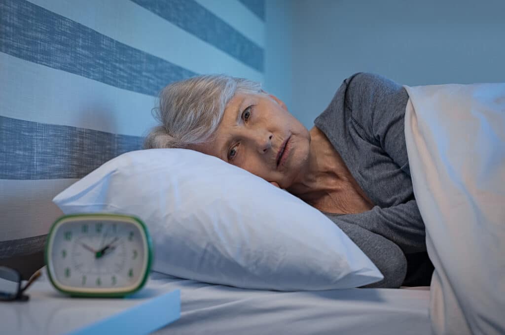 Image of an older woman awake watching the clock from hip pain while sleeping