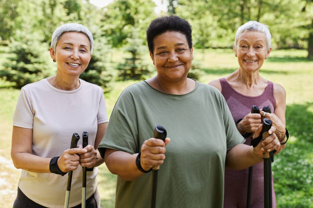 Walking poles for seniors: three older women outdoors preparing for a workout with walking poles