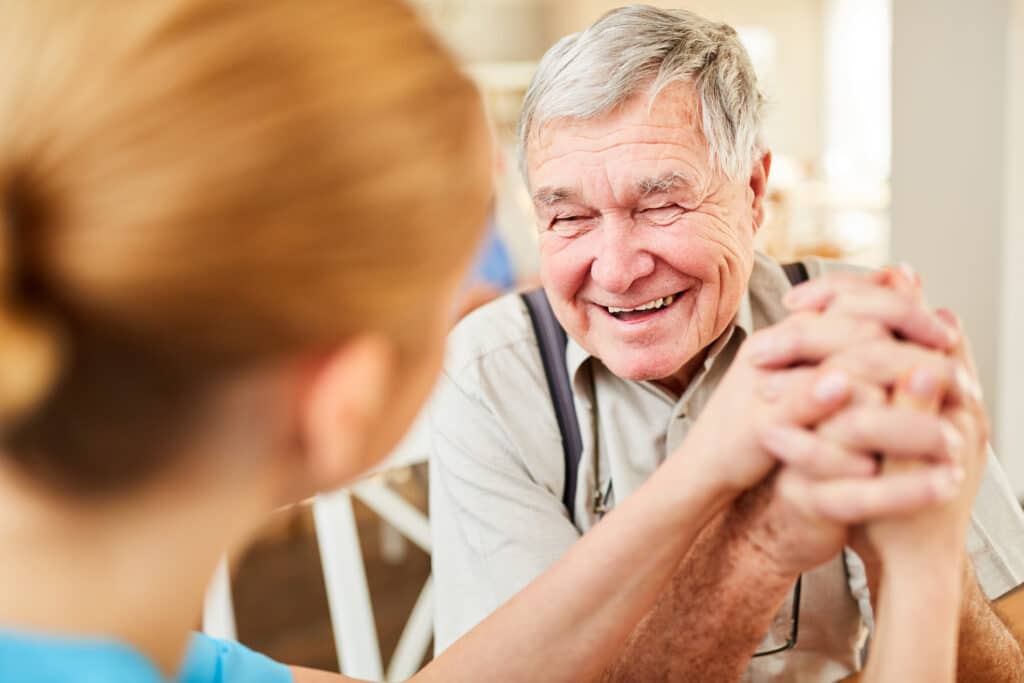 Image of an older man with a hopeful smile after a physical therapy session with his therapist.