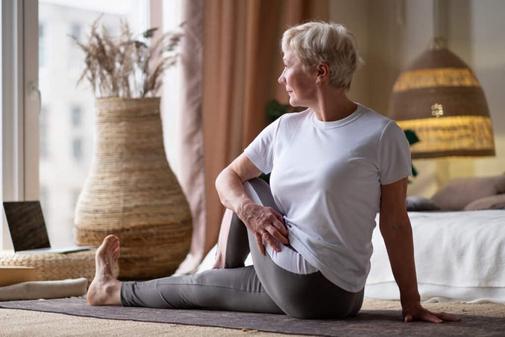 How to decompress spine at home — Image of an older woman doing a seated twist yoga pose for spine health. 