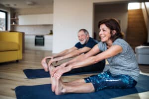 Image of happy senior couple stretching together as part of their daily exercise routine.
