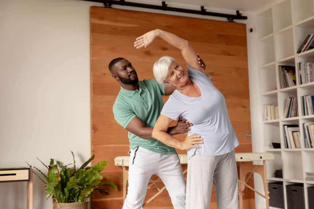 Stretching vs strengthening: an african american PT helps his patient stretch.