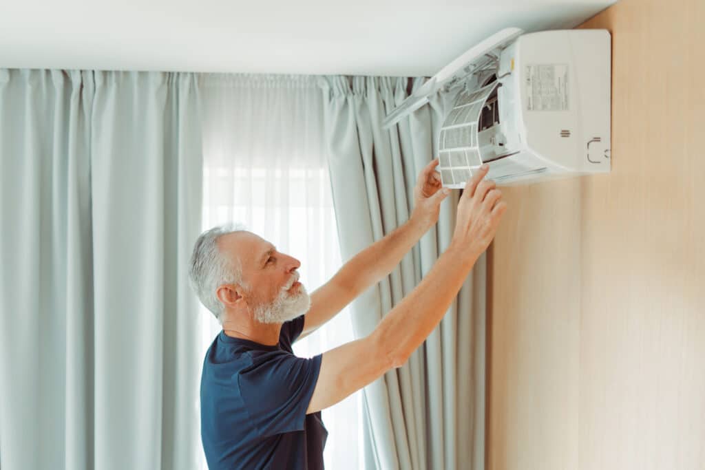 Dealing with the heat: A senior man replaces his air conditioning filter
