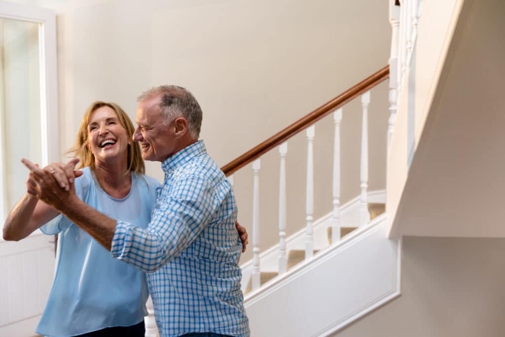 Why People Move Slower as they age: image of a senior couple dancing by the stairs in their home