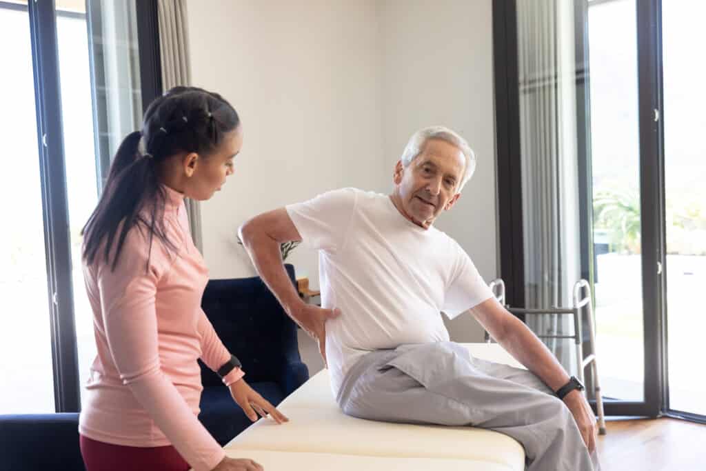 Lumbar Traction: Image of a senior man being assessed by a physical therapist for low back pain