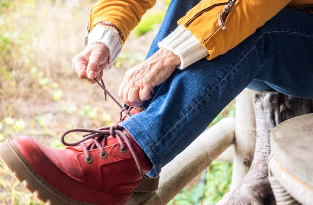 The best shoes for bunions: a senior woman laces up her hiking boots