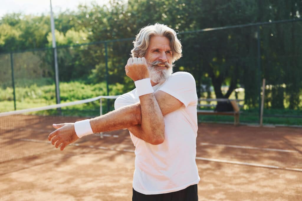 Shoulder crepitus: a senior man stretches his shoulders before a tennis match