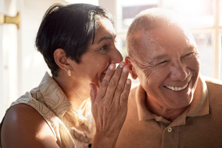 Hearing Loss and Brain Health: A senior couple playfully whisper to each other