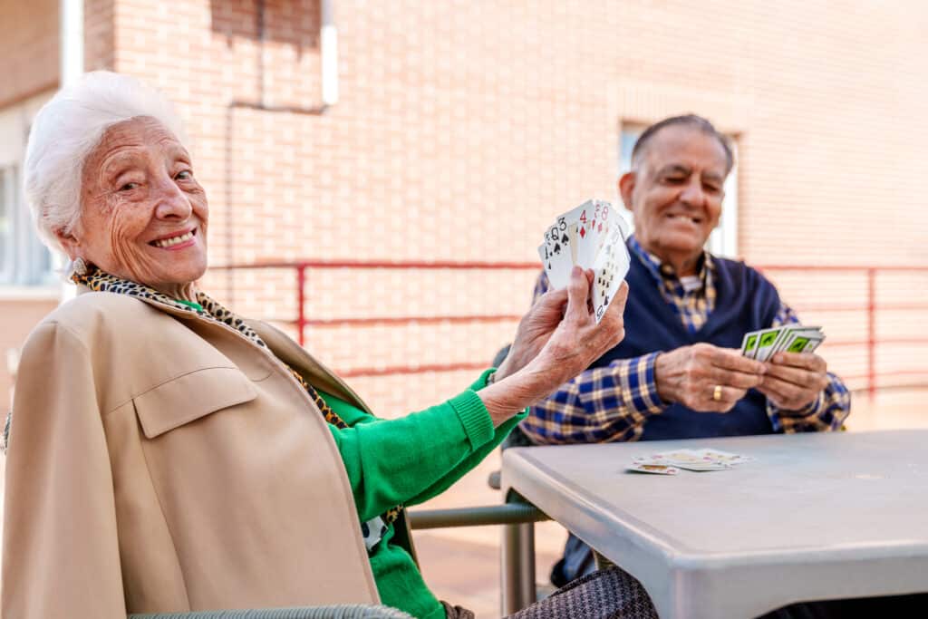 A senior couple plays cards outside their apartment building