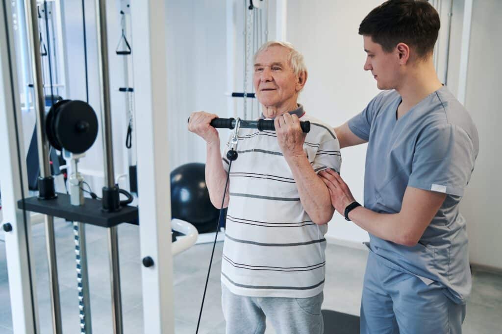 Elderly patient perforing activity on pulley weight training equipment