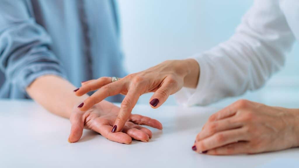 Examining the hand of a senior patient with carpal tunnel syndrome.