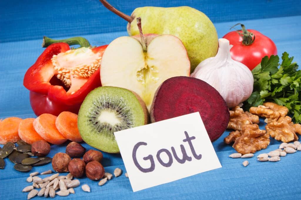 Image of healthy foods with a placard reading "gout" in the foreground.