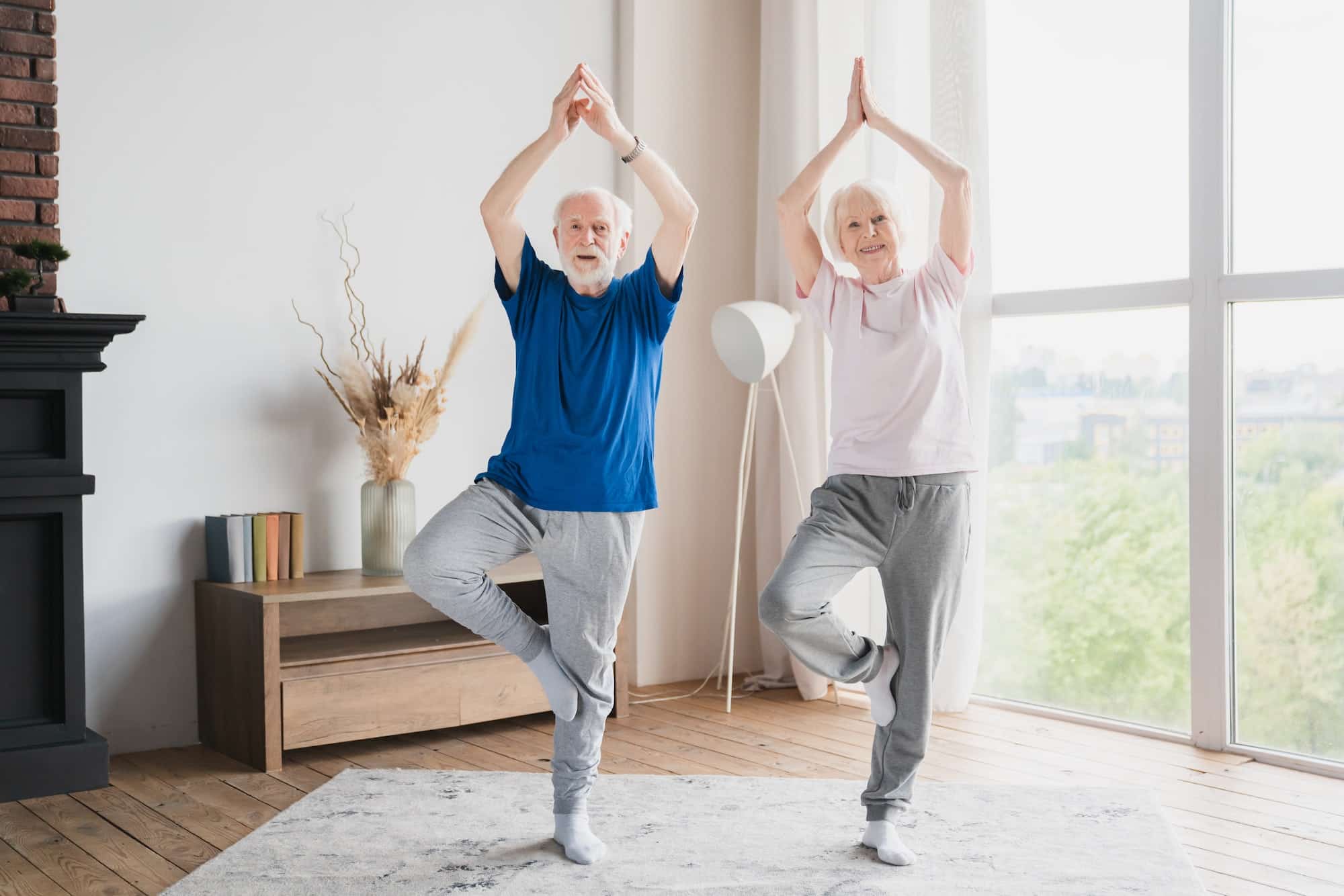 Grandparents training stretching doing yoga exercises at home on lockdown together keeping balance