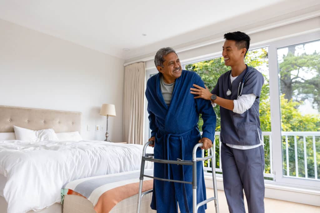 A senior man receives assistance with his walker in his bedroom as part of his aging in place strategy