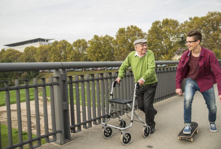 Rollator walker style and function: image of a man with a Rollator walker walking with his grandson on a skateboard