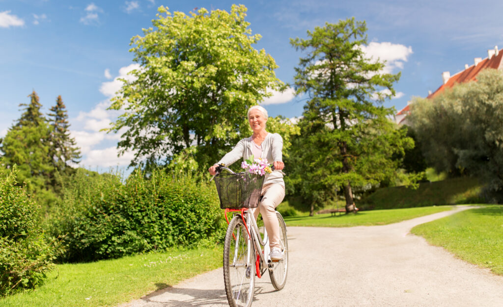 A smiling senior woman rides a bike on a beautiful summer day