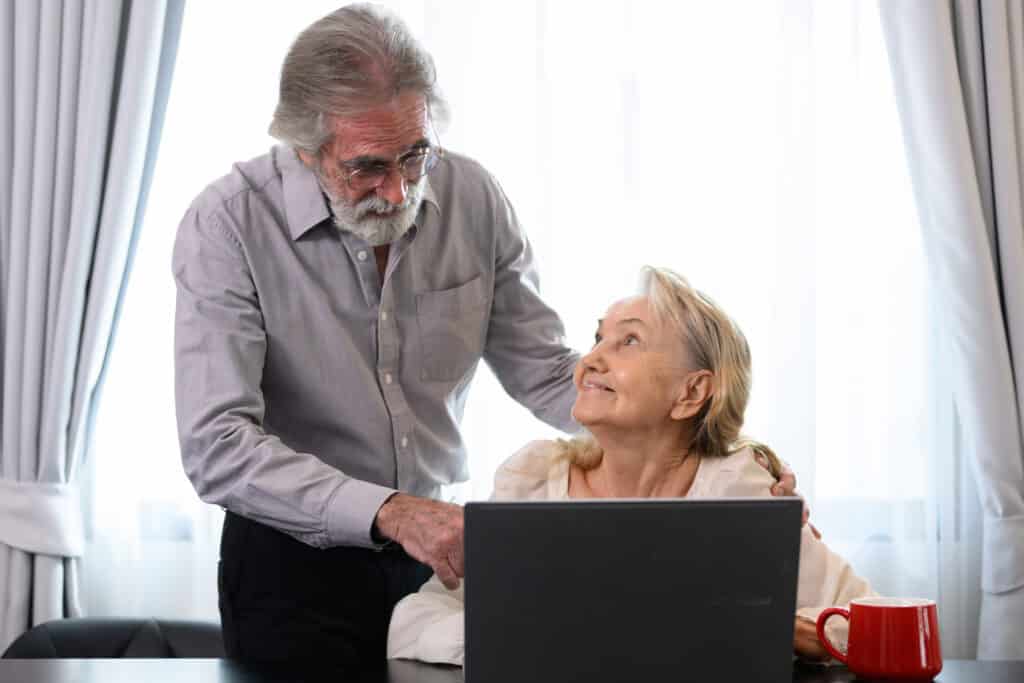 Telerehabilitation in Physical Therapy: a senior man helps his wife use her computer