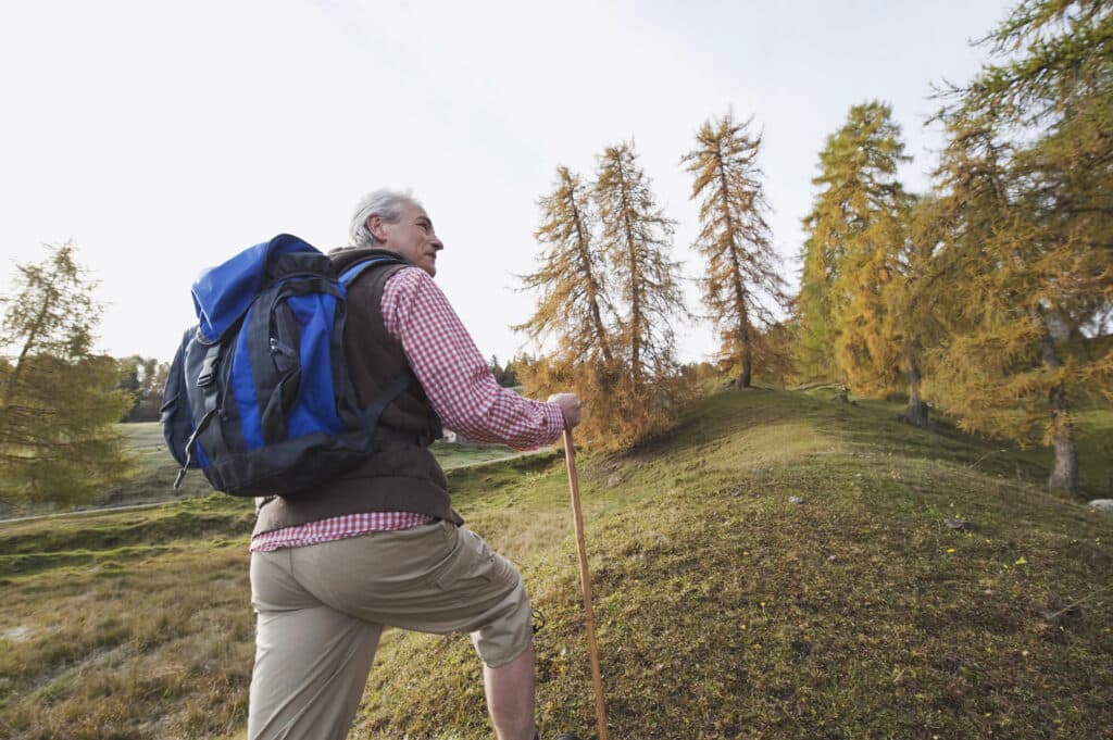 Image of a senior man hiking without knee pain while squatting or doing other activities