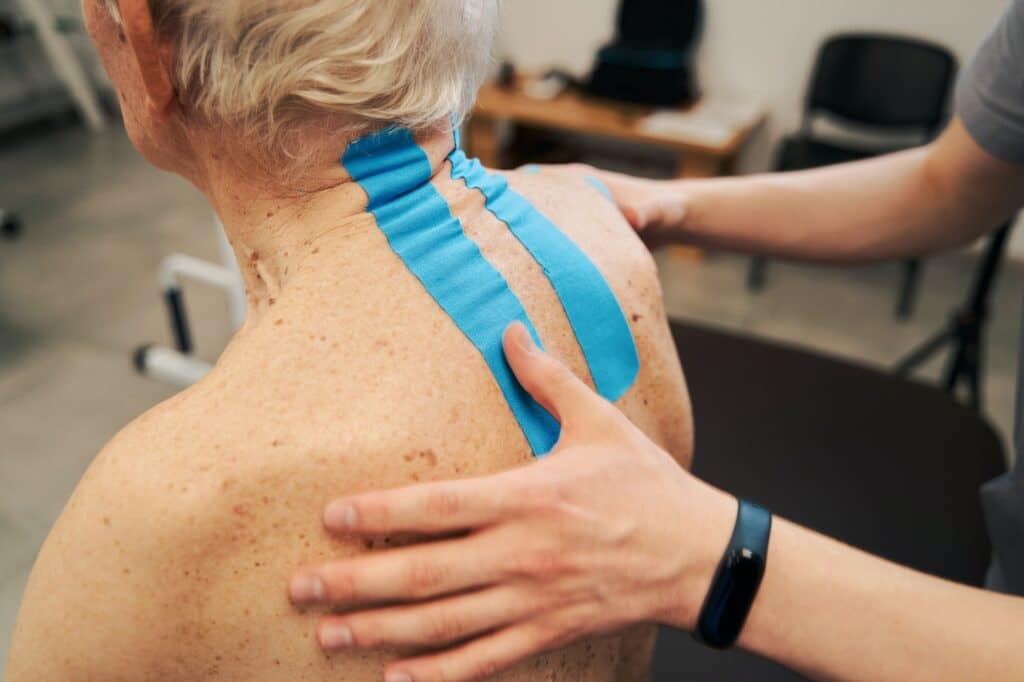 Kinesiology therapeutic tape treating wrinkled back skin of pensioner