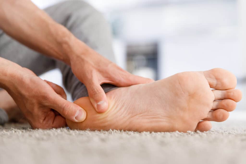 Image of a man rubbing his heel on a carpeted floor.