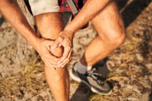 Image of a man with bursitis outdoors holkding his knee