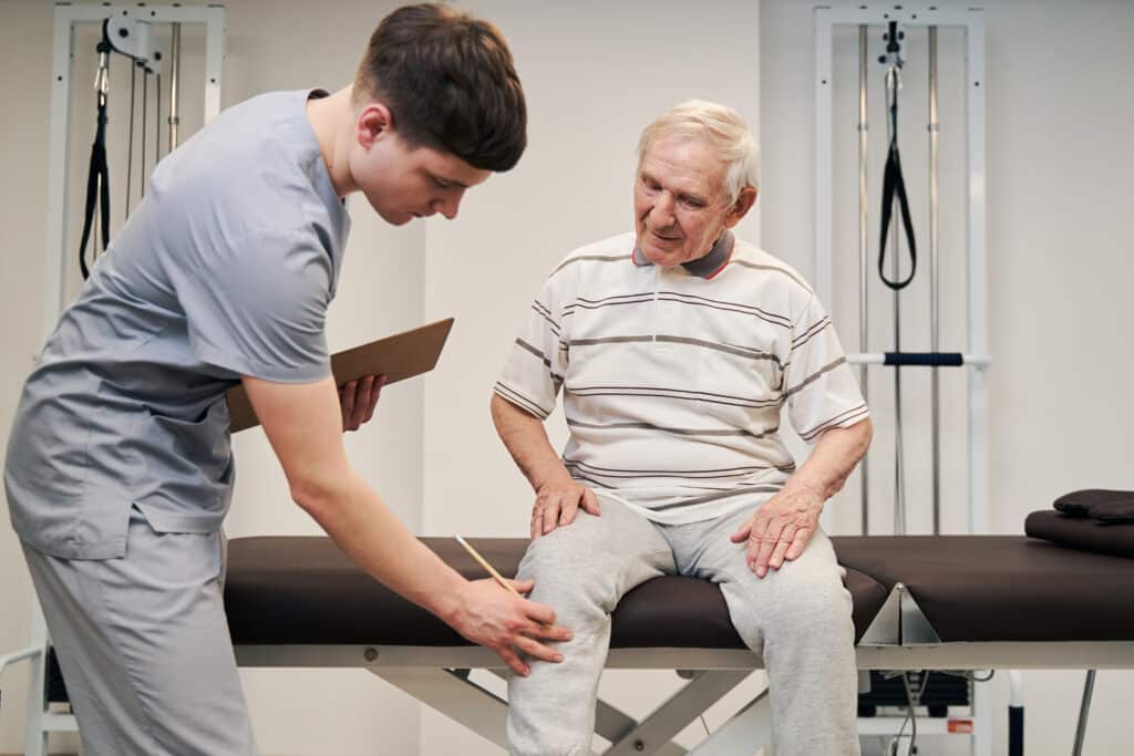 Knee pain when going up stairs: image of a senior man at a physical therapy appointment for knee pain.