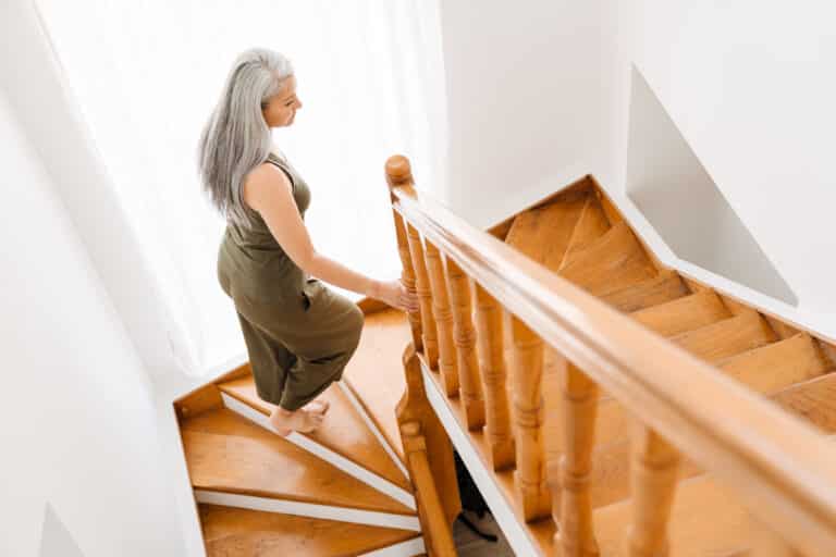 Knee Pain While Going Up Stairs Image of a senior woman walking up stairs